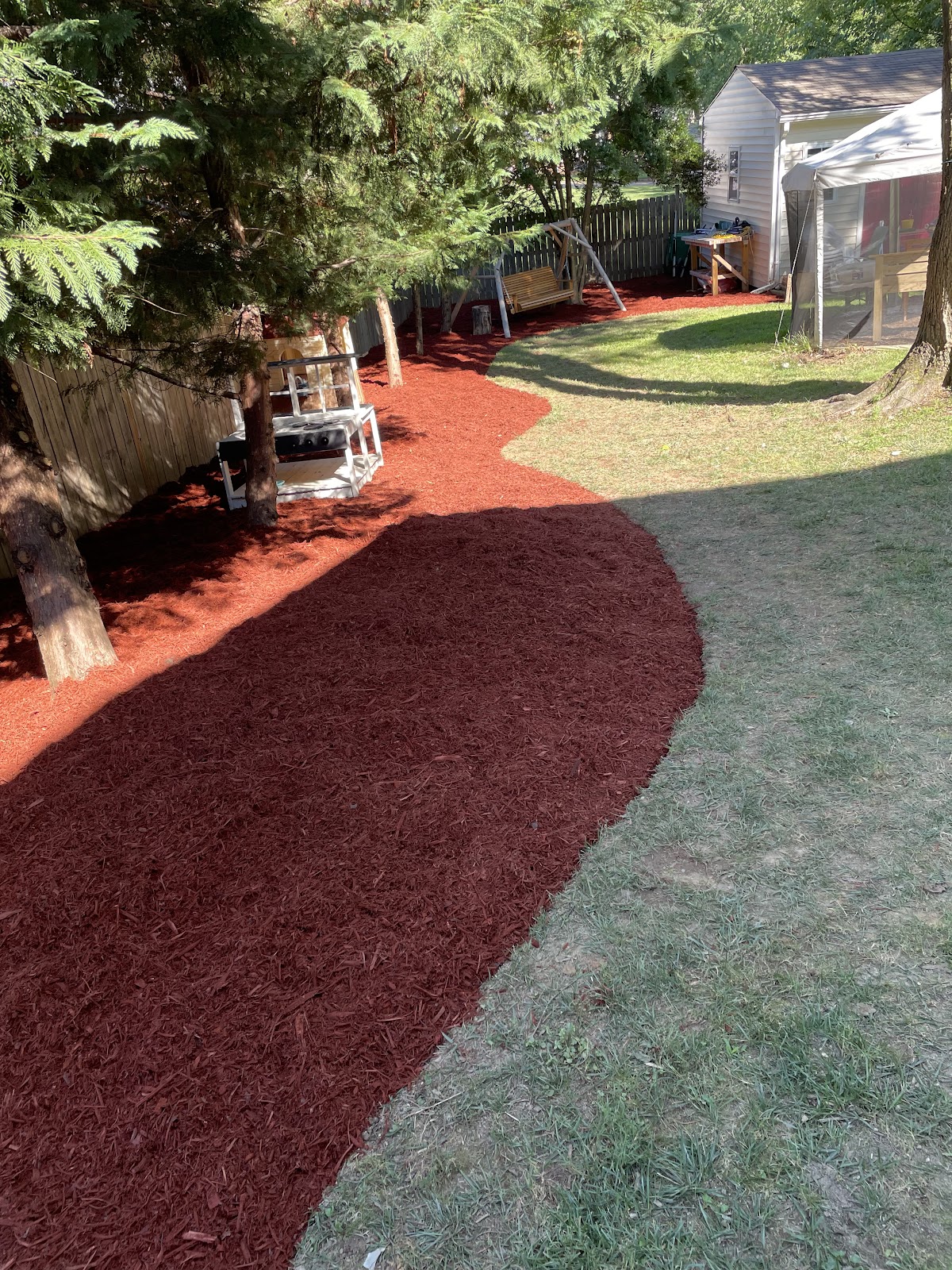 Curved red mulch bed winding through a green lawn